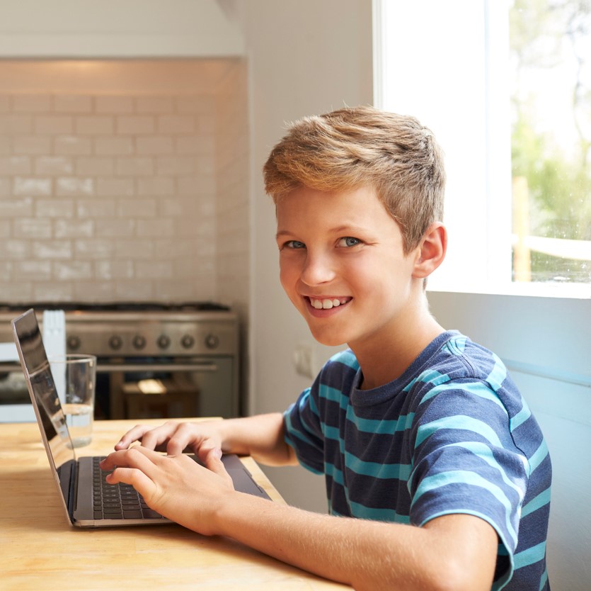 Portrait Of Boy At Home Using Laptop On Kitchen Table
