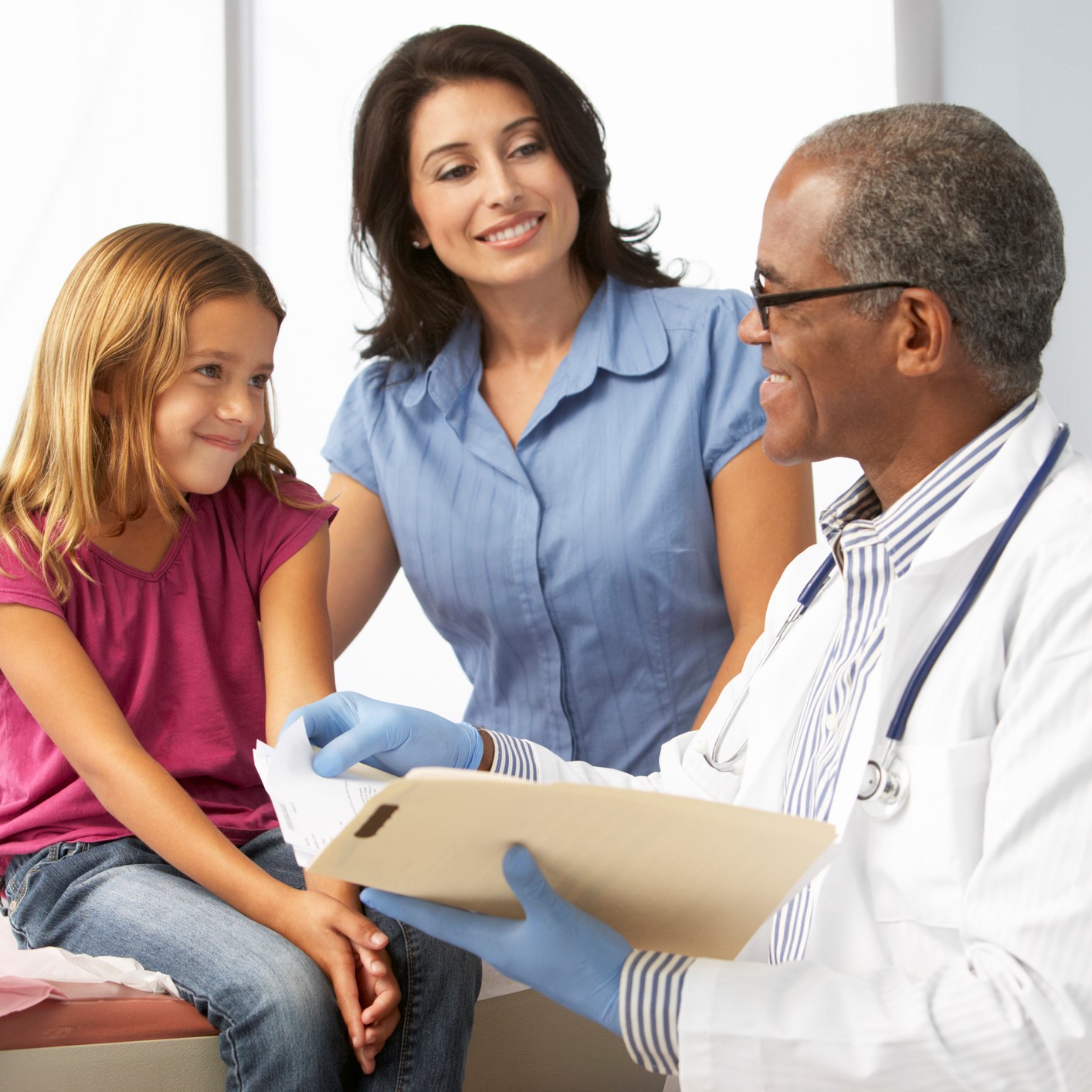 Smiling doctor examining young girl with mother.